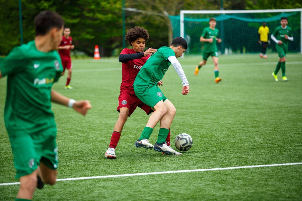 Deux jeunes joueurs de football en maillot courant sur le terrain lors d’un match de la catégorie U11 à U13.